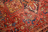 Rectilinear geometric floral patterns with serrated leaves in brick red on a vintage Heriz carpet.