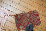 Antique Yastik rug showing geometric medallion pattern, cinnabar red field, and frayed ends.