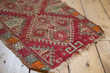 Antique Yastik rug detail: tattered edge, cinnabar, green serrated hook motifs, wear to knot heads.