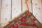 Antique Yastik rug mat corner with tattered fringe and red, blue, ivory serrated design.