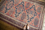 Elongated navy and blush geometric medallions on a madder root red field of this vintage Soumac carpet.