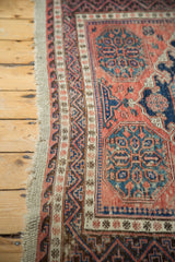 Intricate geometric border with tattered side of the Soumac carpet in faded red and navy.