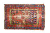 Vintage Caucasian rug with geometric designs, central mehrab, red, blue, and visible foundation.