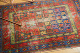 Brick red, deep blue, green geometric patterns with worn pile on a vintage Caucasian rug.