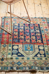 Vintage Caucasian prayer rug's lower geometric border with plant motifs and visible tatter.