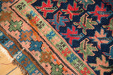 Geometric madder red, pistachio green, and blush plant motifs on vintage Caucasian rug with tatter.