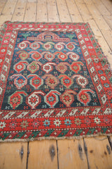 Antique Caucasian rug: oversized botehs on indigo field with red starburst border.