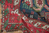 Antique Caucasian rug displaying rich indigo, cochineal red starburst border, textured pile, and worn fringe.