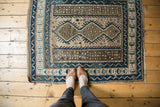 Vintage Caucasian rug showcasing its geometric triple medallion in blue and brown tones.