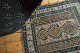 Geometric field pattern of a vintage Caucasian rug, with charcoal brown, cobalt blue, and silver pearl fills.