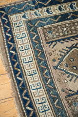 Vintage Caucasian rug corner: cobalt blue geometric meander border, serrated patterns, and aged fringe.