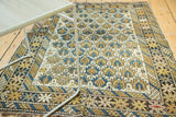 Antique Caucasian rug showing detailed geometric splayed floral field pattern in gold, sky blue, and ivory.