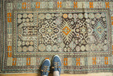 Antique Caucasian rug corner with geometric patterns, tangerine orange, sky blue, and soft wear.