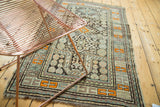 Geometric pinwheel and rams horn motifs with tangerine border on an antique Caucasian rug.