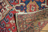 Detail of vintage hand-knotted Karaja rug showing red, navy, ivory geometric pile and woven back.