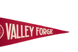 Angled close-up of vintage red felt pennant with 'VALLEY FORGE' in aged white text.