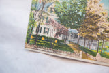 Angled close-up of the vintage postcard showing its printed texture and caption.