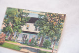 Angled view of the vintage Mountain Breeze House postcard showing lush trees and printed text.