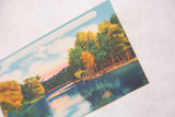 Angled close-up of the vintage postcard showing the texture of the printed lake scene.