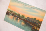 Printed location text over the peachy and blue sky on a vintage postcard.