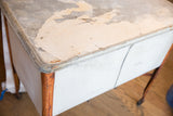 Vintage farmhouse wash tub lid with peeling white paint and rusted galvanized metal.