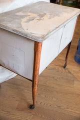 Vintage wash tub with peeling white paint on its galvanized lid and rusted orange legs.