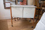 Rusted orange leg and working caster wheel of the galvanized farmhouse wash tub.