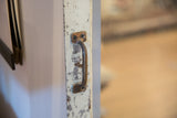 Rustic metal handle detail on mirror's distressed white painted copper door.