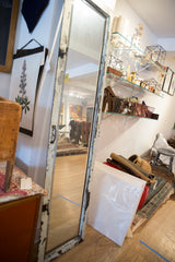 Chipped white paint on the reclaimed copper door mirror's distressed frame detail.