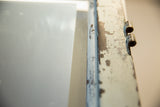 Close-up of peeling paint and rustic copper hinges on the vintage door mirror frame.