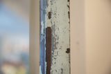 Chipped layered pale paint texture on the vintage 1930s copper door mirror frame.