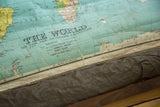 Detail of antique pull down map's creased blue-green canvas and its aged dark roll.