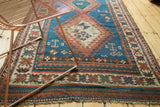 Geometric diamond medallion with hook and latch motifs on indigo blue vintage Caucasian rug.