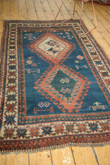 Vintage Caucasian rug's lower right corner, showing herdsman and animal motif on indigo field.