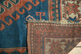 Vintage Caucasian rug detail: indigo blue pile with hook and latch motif, and terra cotta foundation.