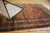 Corner of an antique Malayer rug, displaying its terra cotta herati field and detailed borders.