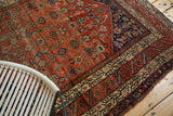 Antique Malayer rug corner: intricate herati motifs and detailed borders in terra cotta and indigo.
