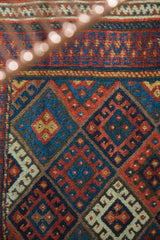 Jaff Kurd rug's tribal geometric gul and hook-and-latch motifs in madder, indigo, and saffron.