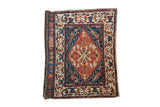 Antique West Persian bag face rug with a large floral medallion in brick red, navy blue, and ivory.