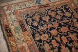Close-up of Kurdish rug's dark indigo field with artistic motifs and contrasting colorful borders.