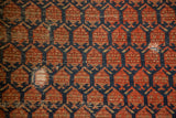 Antique Malayer rug's repeating dark indigo and rust boteh design, with foundation showing.