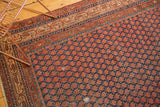 Antique Malayer rug detail showing repeating boteh design, indigo, rust and visible foundation.