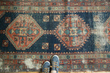 Antique Heriz runner: stepped geometric medallion, indigo, faded red, visible wear.