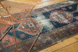 Angled detail of antique Heriz runner, faded brick red and indigo geometric patterns with foundation showing through.