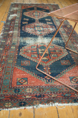 Rectilinear geometric pattern of antique Heriz rug in indigo, brick red, showing wear.
