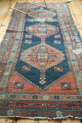 Worn texture of stepped brick red and indigo geometric motifs with tattered fringe.