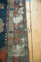 Antique Heriz rug's geometric border, showing wear, exposed foundation, indigo, and red.