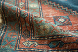 Antique Heriz rug pile detail: rectilinear design in faded brick red and slate blue.