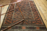 Antique Belouch rug's geometric scrolling main border and allover trellis pattern in terra cotta and charcoal, with patina.