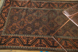 Corner of antique Belouch rug, showing oversized terra cotta meandering border and lattice motif.